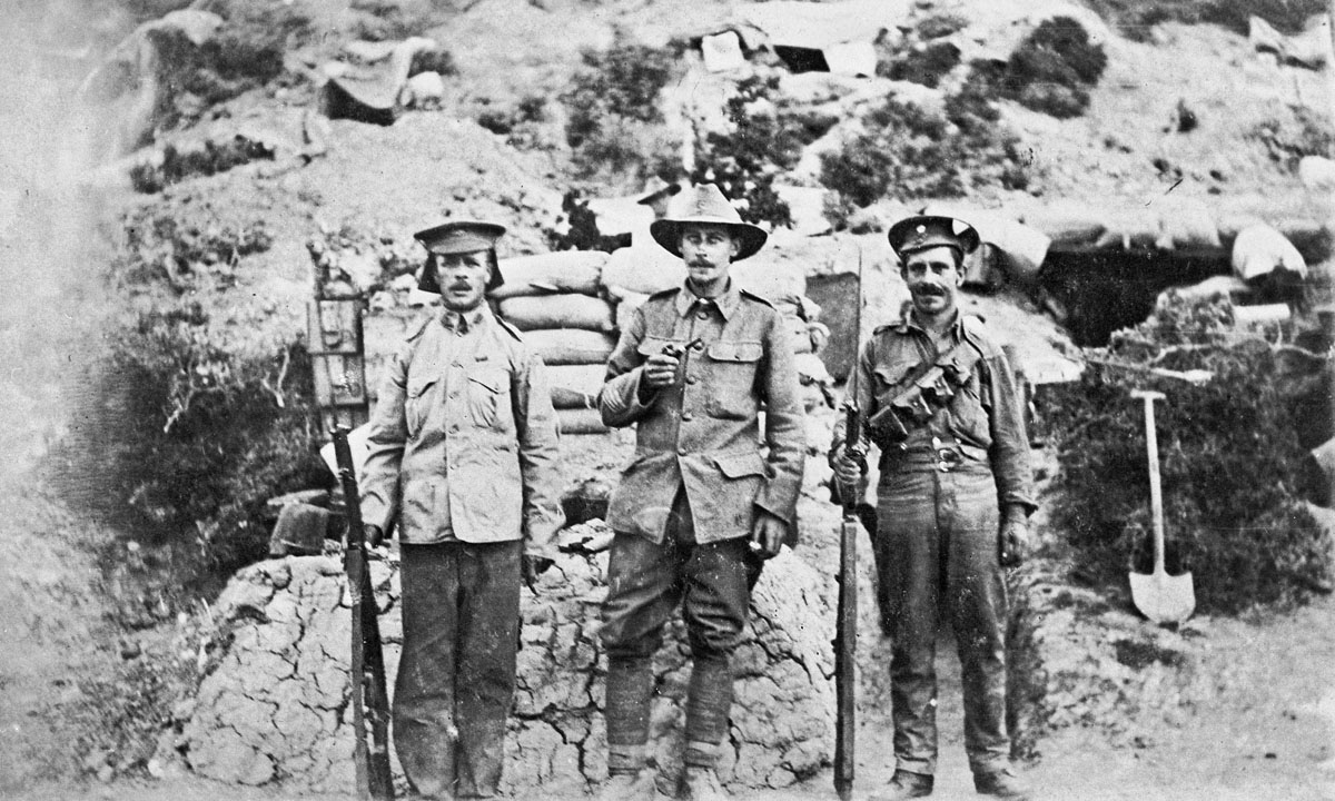 An Australian soldier flanked by two armed British soldiers.